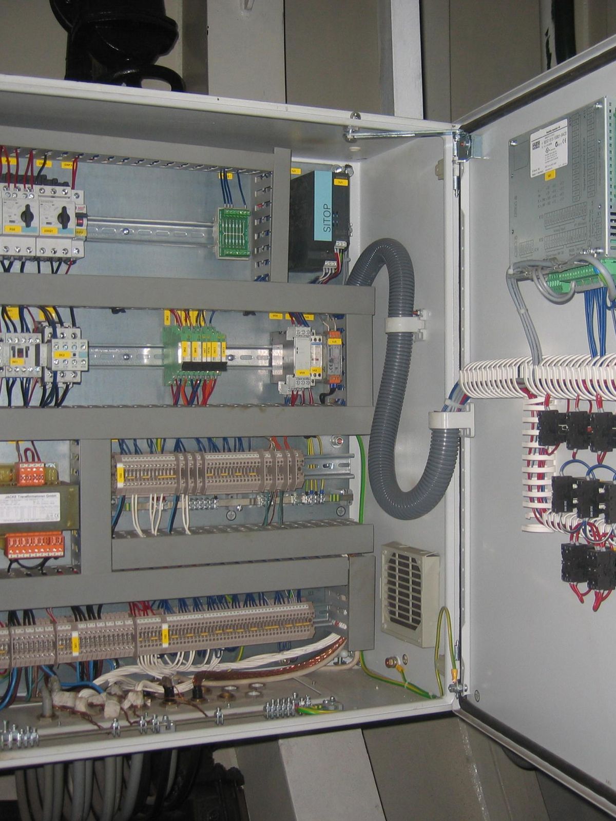 Kapağı açık PLC otomasyon panosu; klemens sırası, PLC ve besleme montajı
